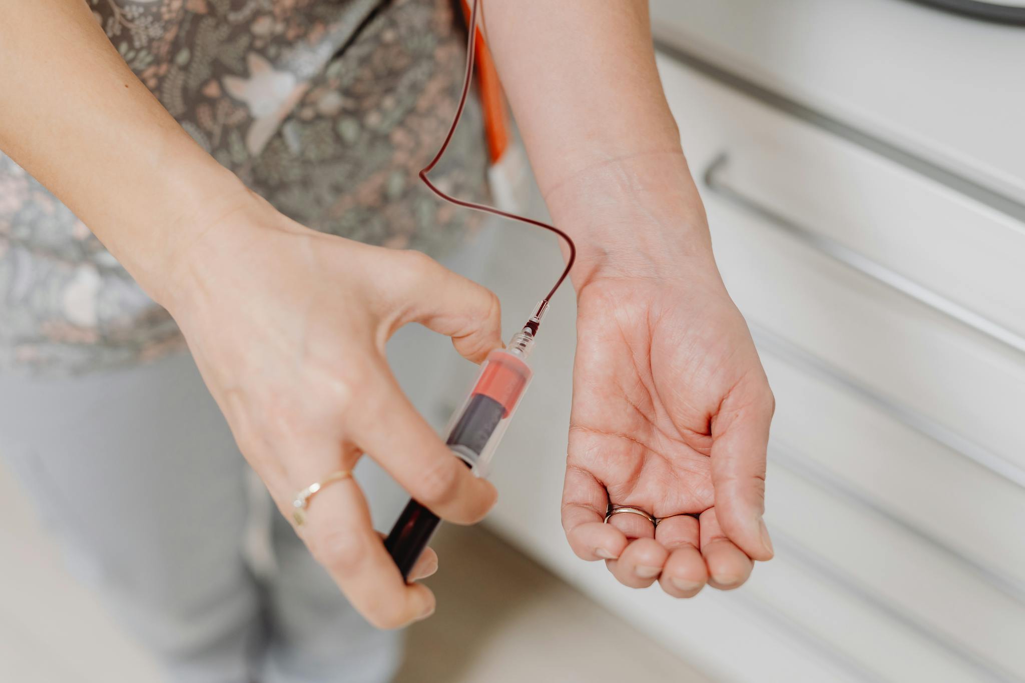 A close-up view of a blood draw procedure with syringe and vial, focusing on healthcare treatment.